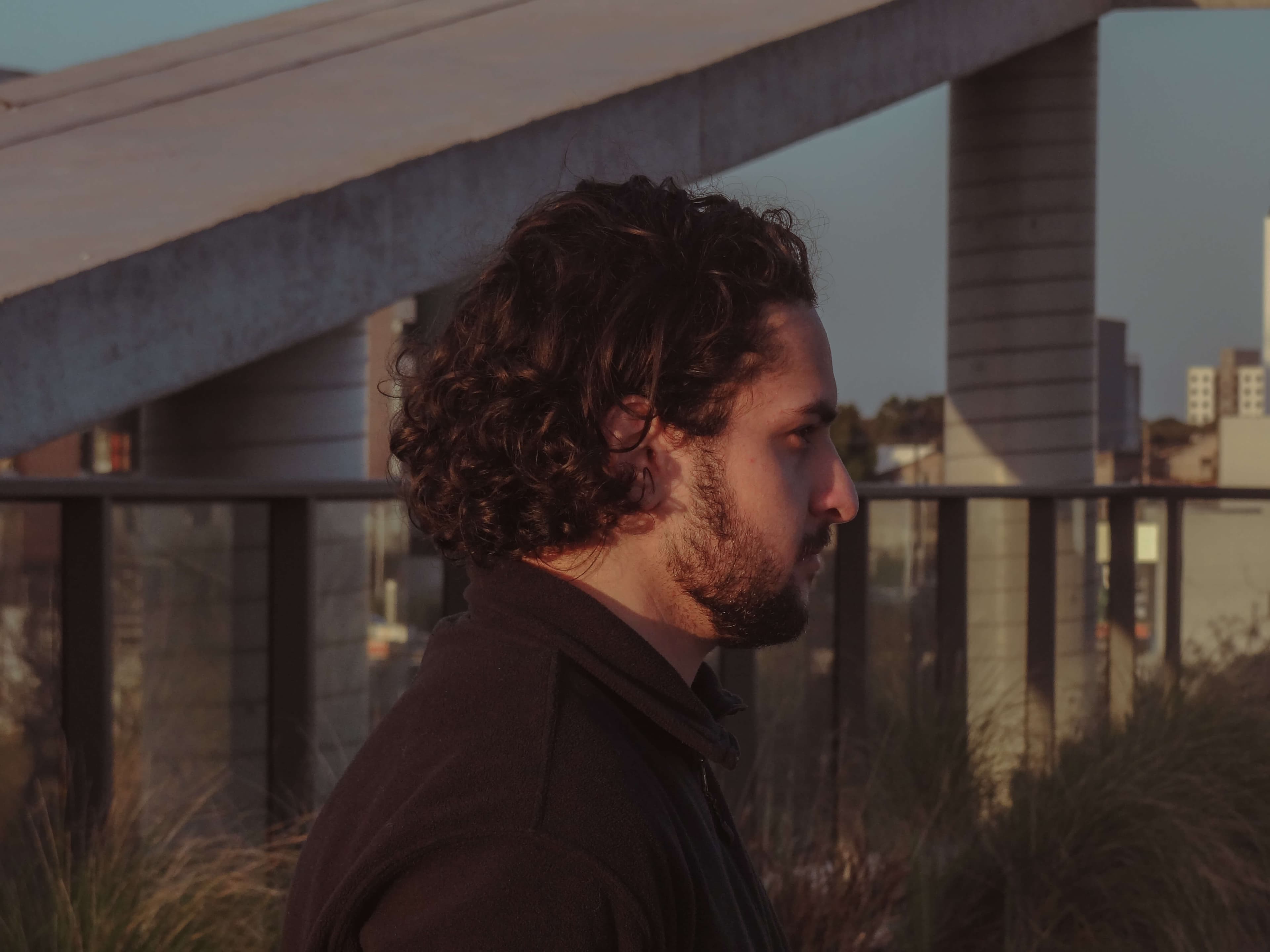 Jonathan in brown t-shirt, with long curly hair in a orange envoriment looking at a woman with white shirt and curly hair.